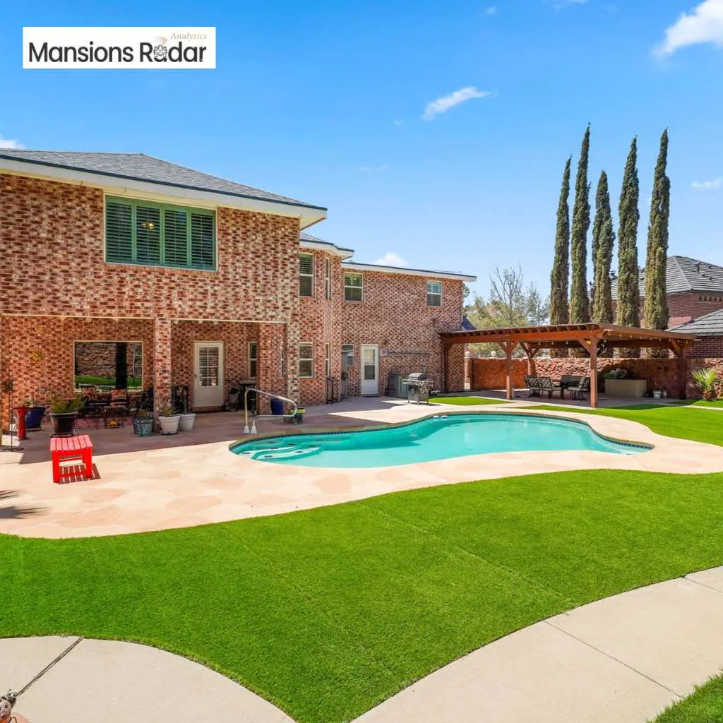 The Johnny Rodriguez house backyard features a beautiful brick exterior, sparkling pool, and a wooden pergola.